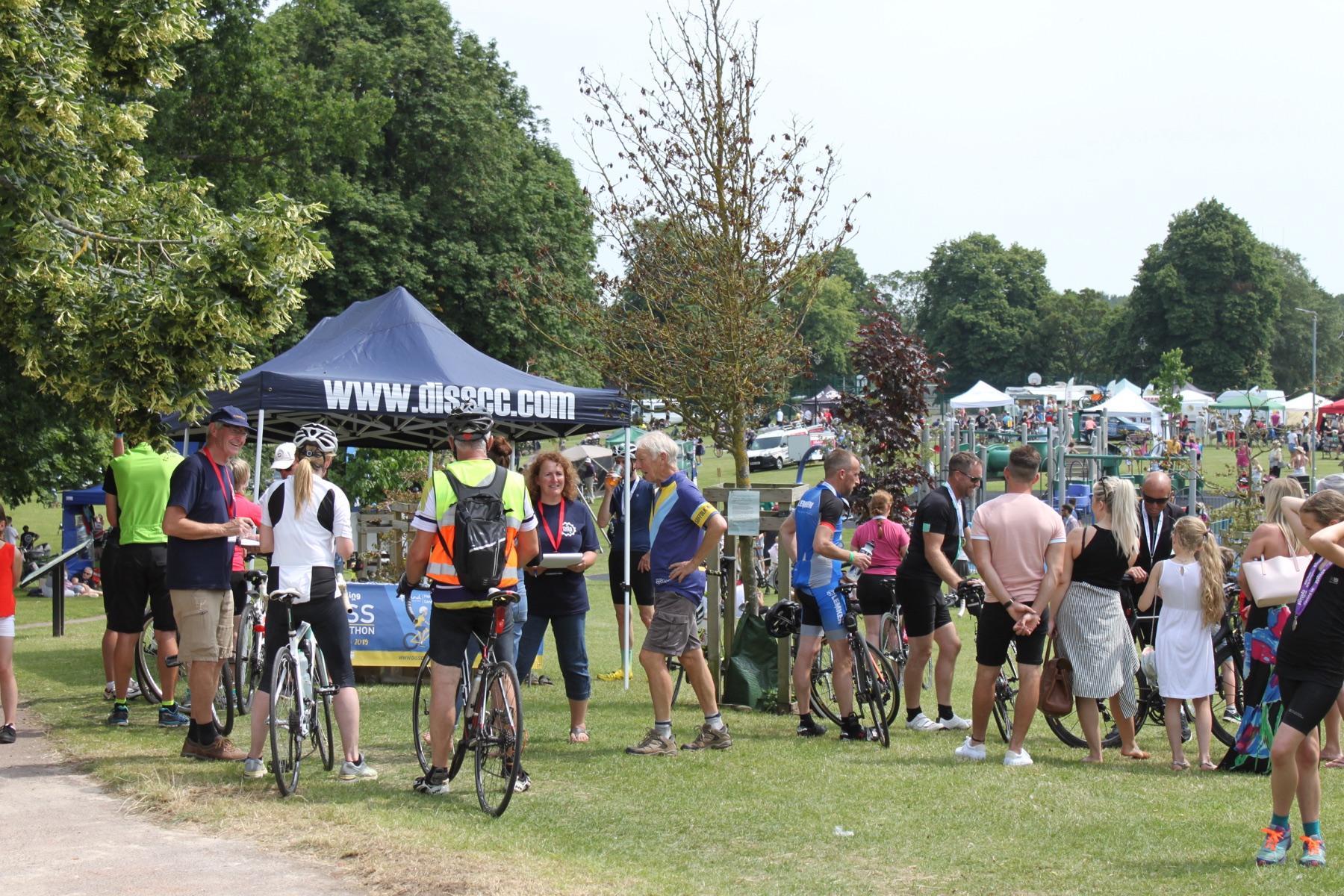 Cyclists and families gathering on a sunny community field