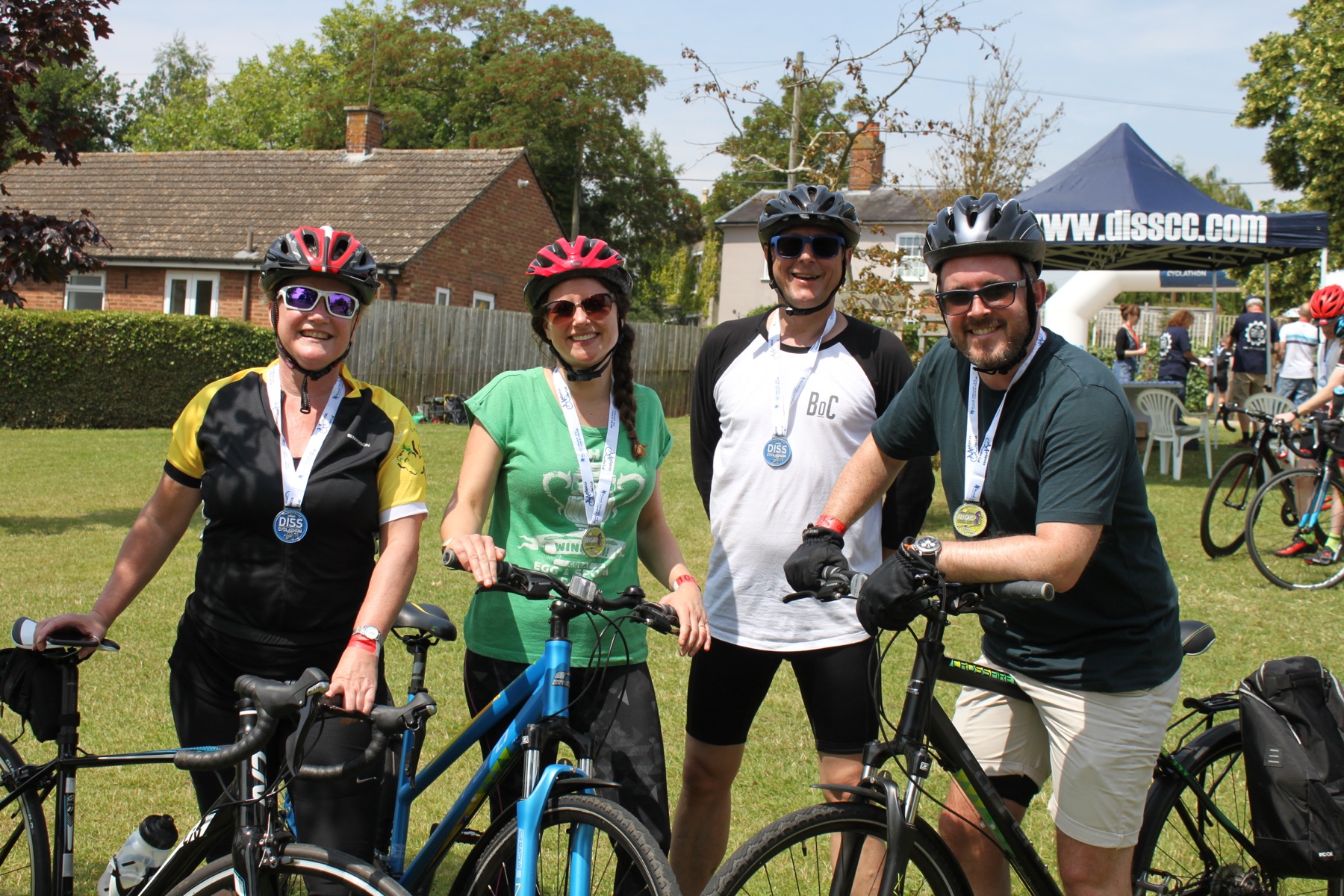 Four smiling riders with their bikes after finishing Diss Cyclathon